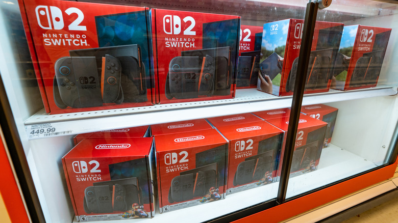Several Nintendo Switch 2 units still in their packaging sit behind a display case in what is presumably a retail store