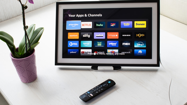 An Amazon Fire TV remote with Alexa sits in front of a small TV using the Amazon Fire TV UI