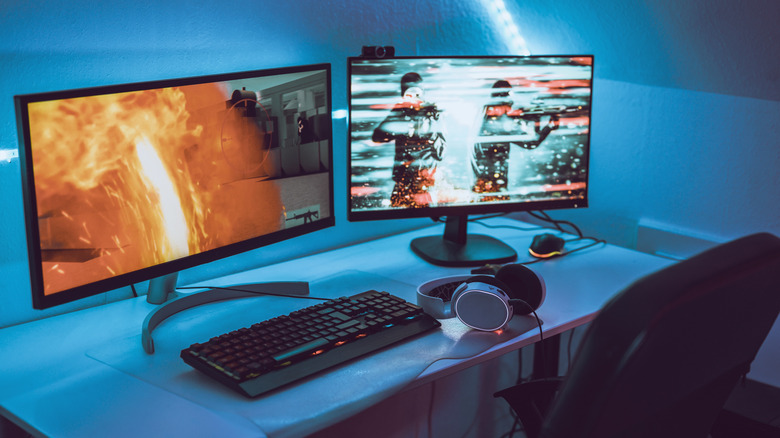 Dual-monitor gaming setup with keyboard, headphones, and blue ambient lighting