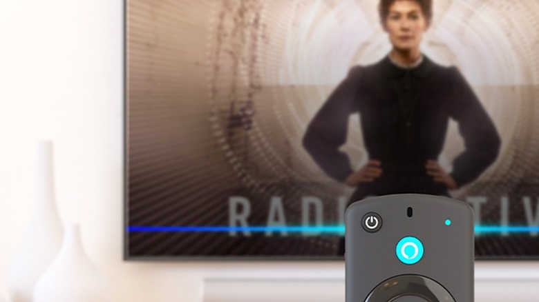 A Fire TV remote with a TV in the background