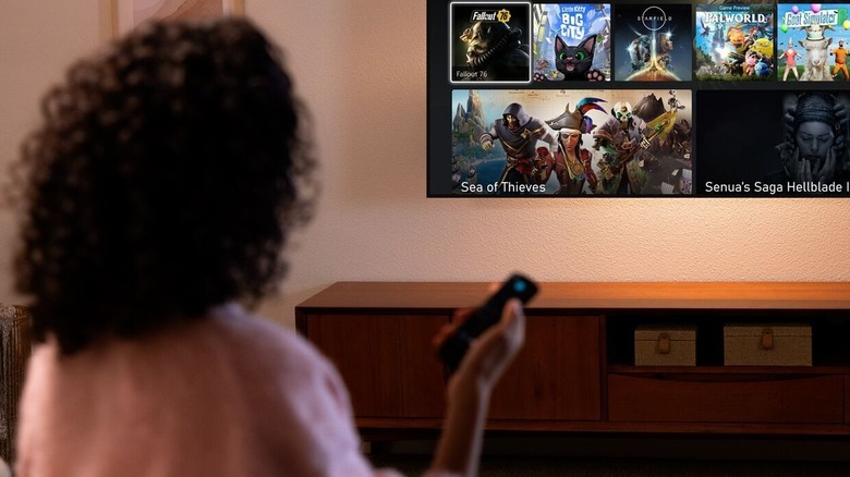 A person pointing a Fire TV remote at a TV