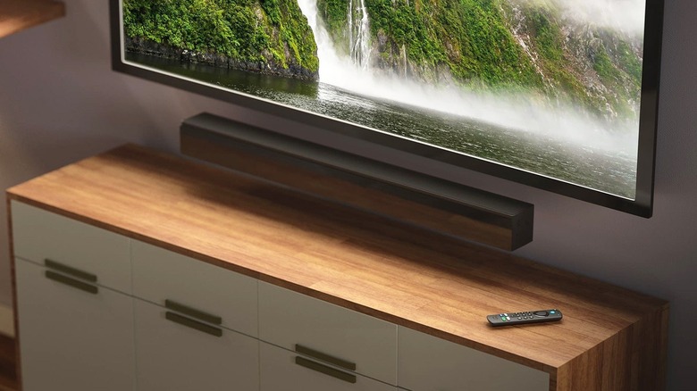 A Fire TV remote on a stand with drawers underneath a TV