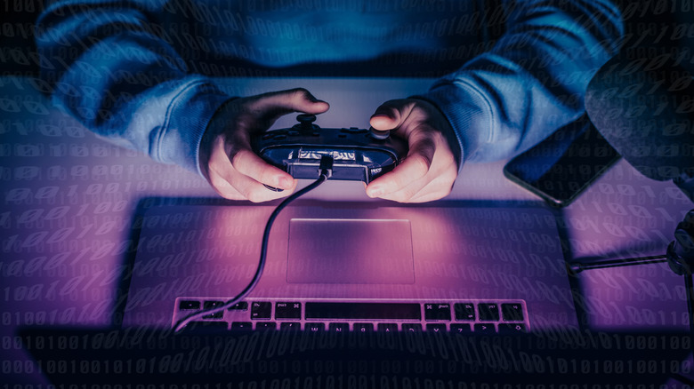 A person playing a game on a laptop with a controller in hand