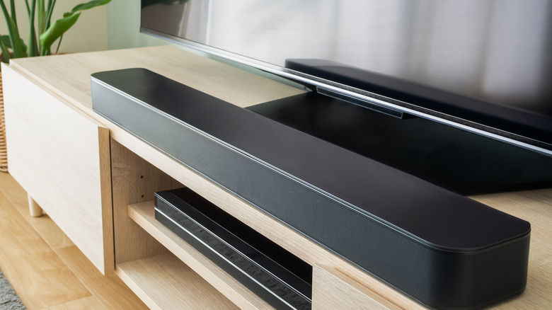 soundbar placed in front of a TV on a wooden cabinet