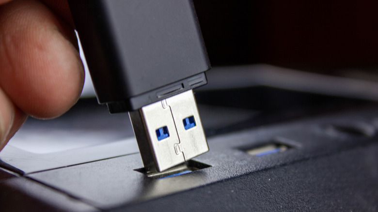 Hand plugging a USB flash drive into a computer