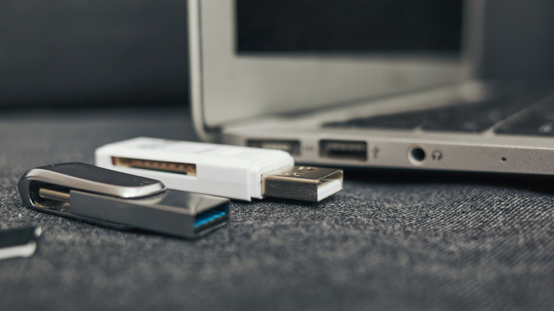 Laptop with a white USB drive and a black USB drive near it