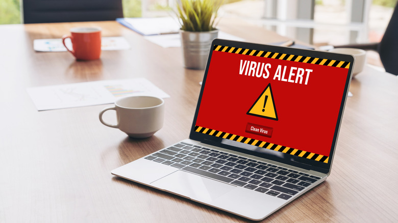 laptop placed on a workstation displaying the Virus Alert message