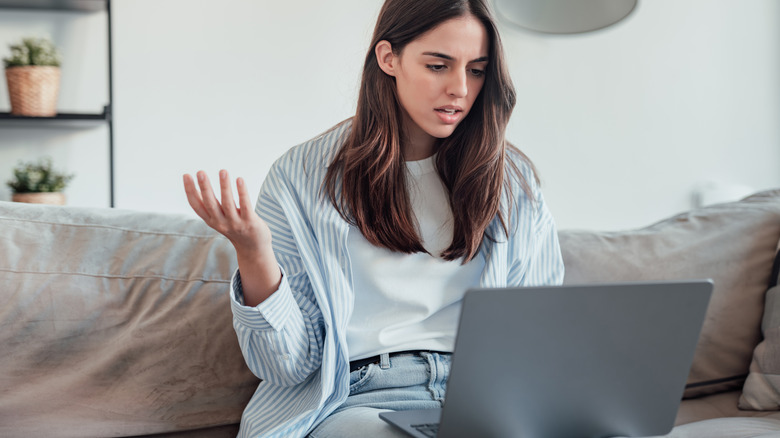 women holding a laptop on a sofa frustrated with slow internet