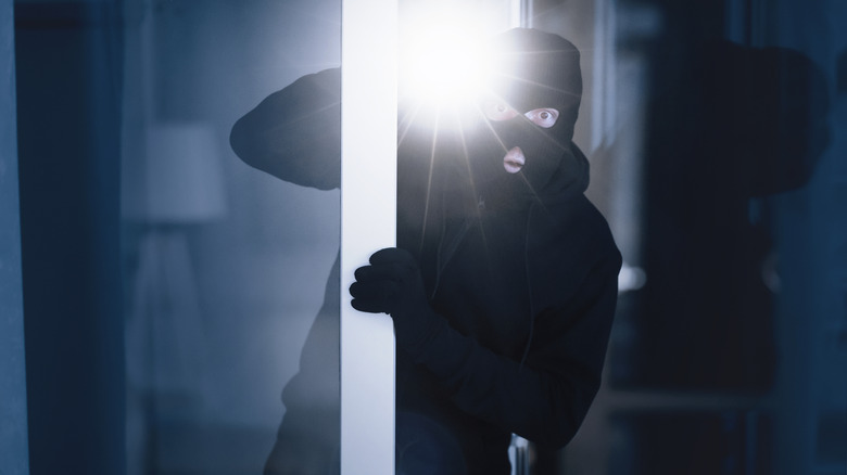 Burglar sneaking into a house with a flashlight