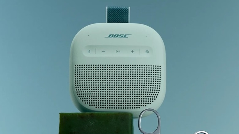 A light green Bose SoundLink Micro sits against a light navy blue background