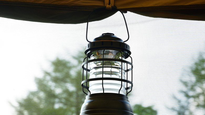A camping lantern hanging from a tent.