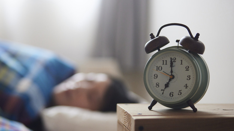 An analog alarm clock placed on a bedside table.