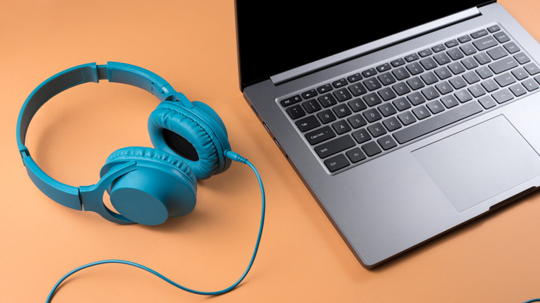 Headphones on a table next to a laptop.