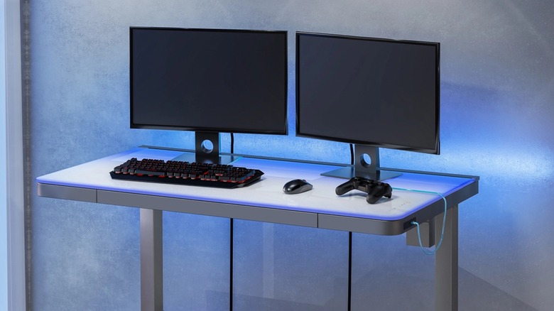 A Tresanti adjustable desk with two monitors and PC accessories on it.