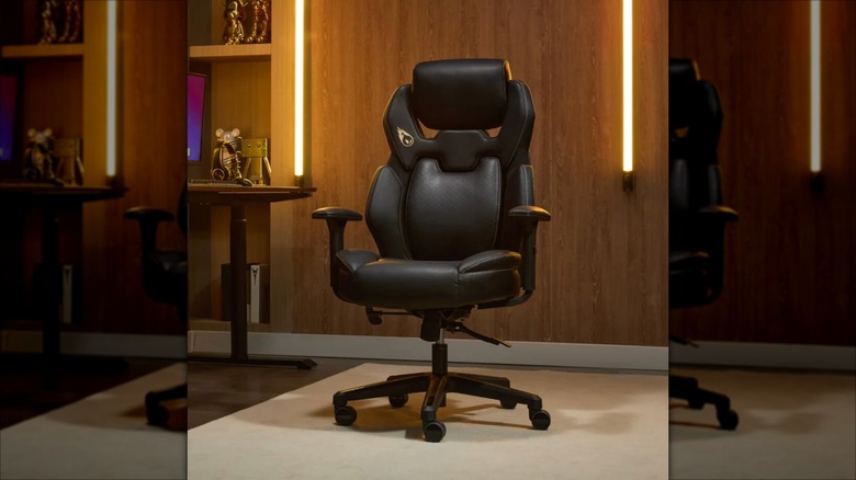 A Costco promotional image for the DPS Encode 3D Insight Gaming Chair, the chair sits in the center of a room with a wood-paneled wall in the background