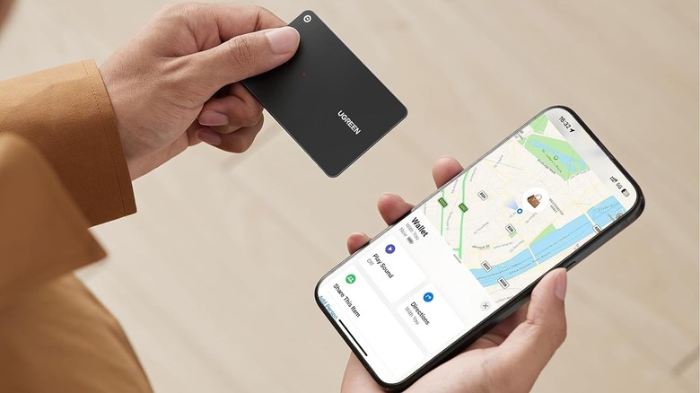 Hand holding the Ugreen FineTrack Slim Wallet Tracker Card with phone