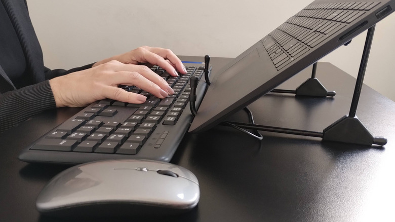 person using external mouse and keyboard with a laptop