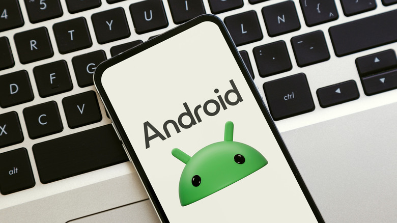 A person holding up a smartphone with an Android logo.