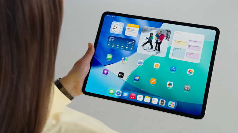Woman holding iPad showing Home Screen with widgets