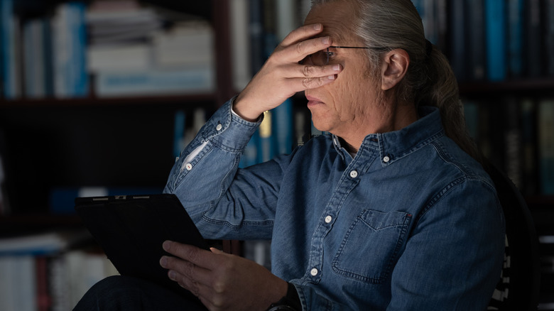 A man reading a scary book on an e-reader