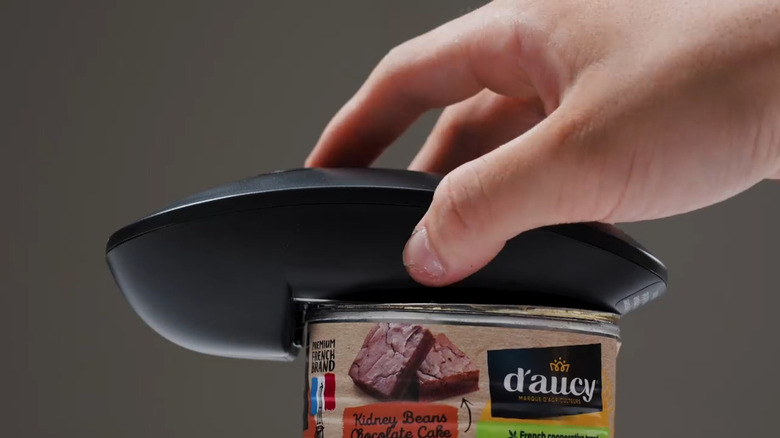 Hand holding Canslab Ultrablade PRO Auto Stop Can Opener on top of can