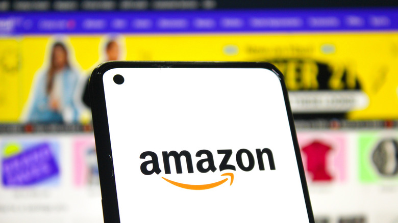 Amazon logo displayed on smartphone with Amazon website in background