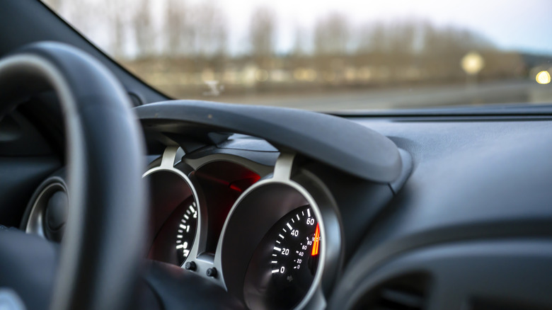 A black and silver dashboard inside a crossover vehicle, and the image also displays half a view of the speedometer