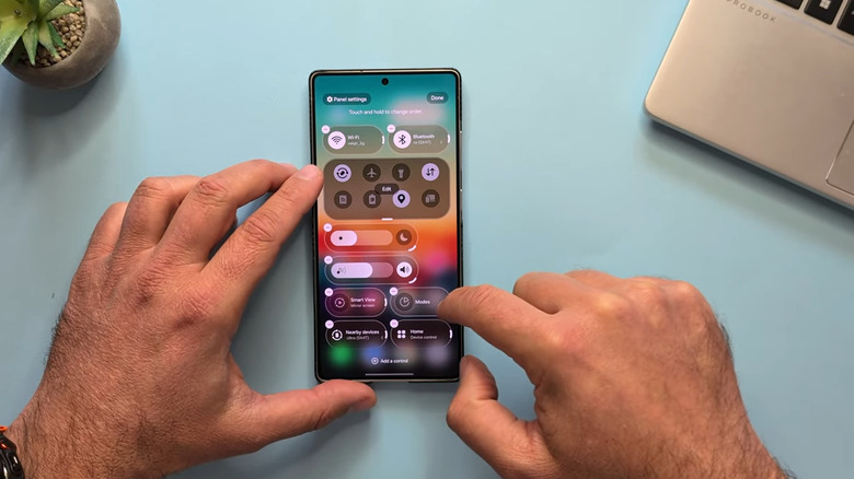 Samsung Galaxy phone on table with hands editing Quick Panel settings