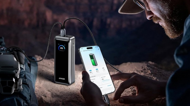 A man charging his phone with an Anker power bank.