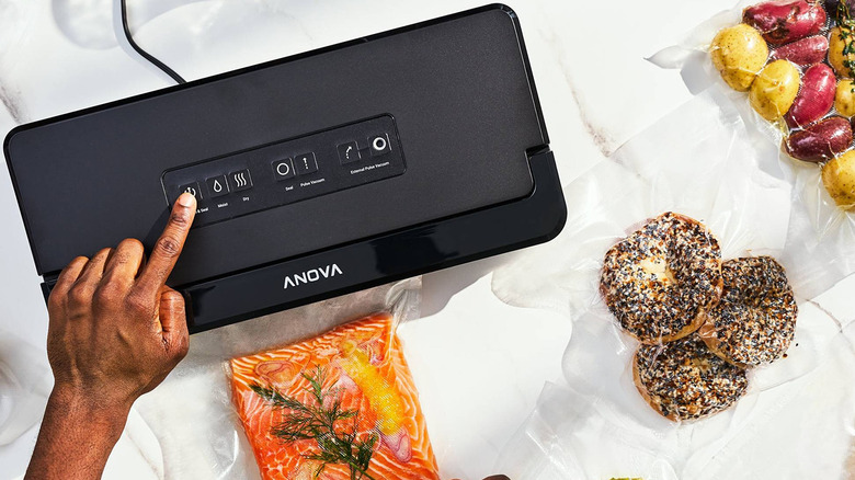 An overhead view of a person vacuum sealing salmon using the Anova sealer.