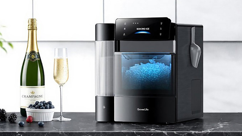 The GoveeLife smart ice maker on a counter with a glass of champagne and fruit.
