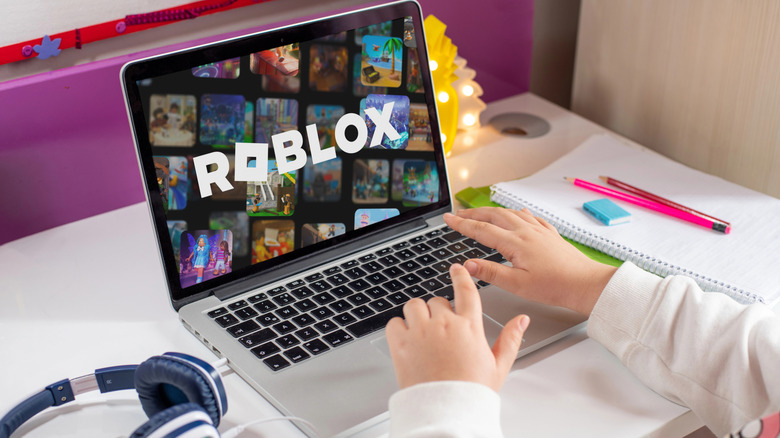 Child playing Roblox on a laptop at their desk.