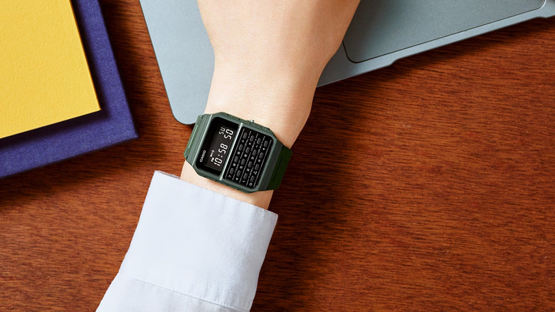 Green Casio CA53W Vintage Series worn on hand while using laptop