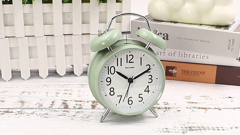 Green Peakeep Analog Alarm Clock on table with books