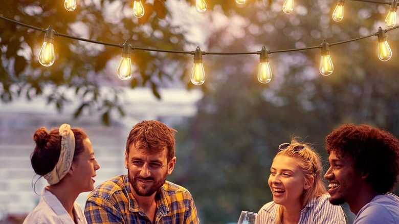 Several people seated under Addlon solar string lights.