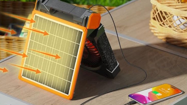 A Kitwlemen Solar Camping Fan receiving sunlight and powering a phone.