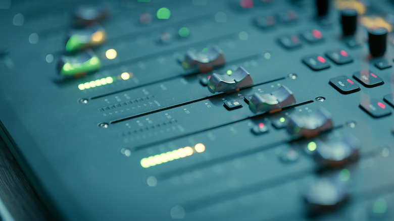 A soundboard with lights, sliders, and knobs