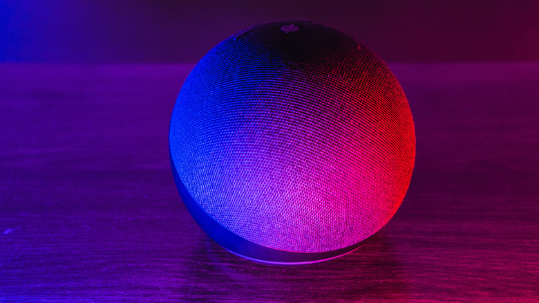 Amazon Echo Dot smart speaker illuminated by a blue and red glow.