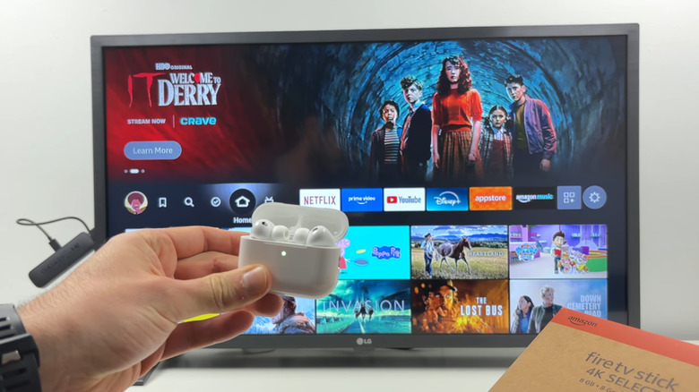 Hand holding AirPods Pro in front of Amazon Fire TV