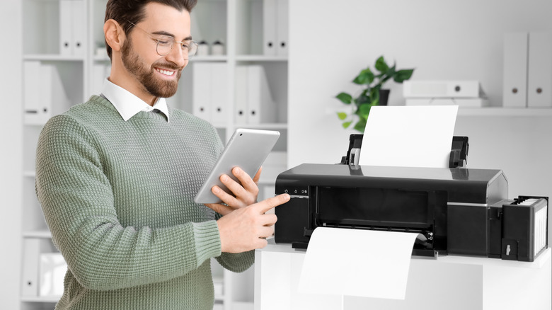 Man printing to a network printer from a tablet in his hands.