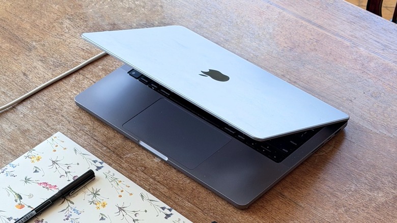 A MacBook Pro half-closed on a wooden table