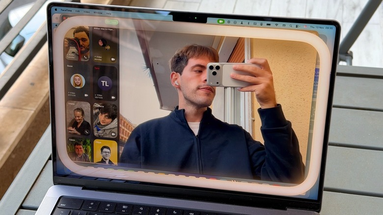 A man pointing the iPhone to a MacBook display with the webcam on