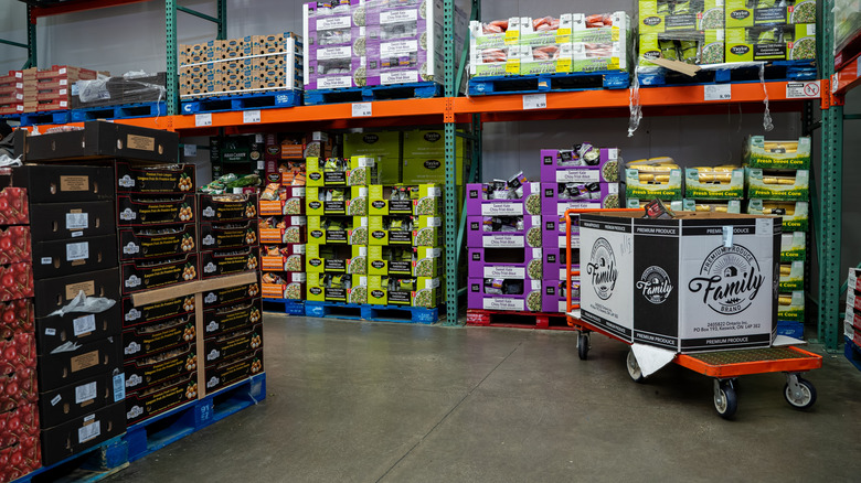 Colorful boxes of fruits and vegetables are stacked and organized neatly onto pallets within the aisles of a Costco store