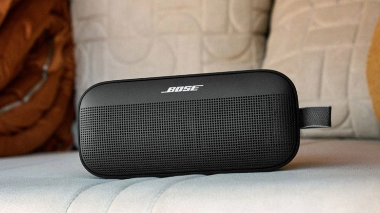 The Bose SoundLink Flex SE Gen 2 Portable Waterproof Bluetooth Speaker on a cushion with pillows.