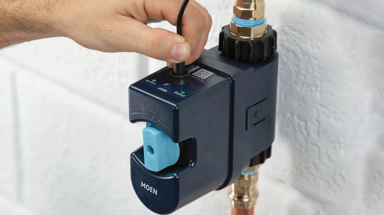 Hand installing Moen Flo Smart Water Monitor into pipe
