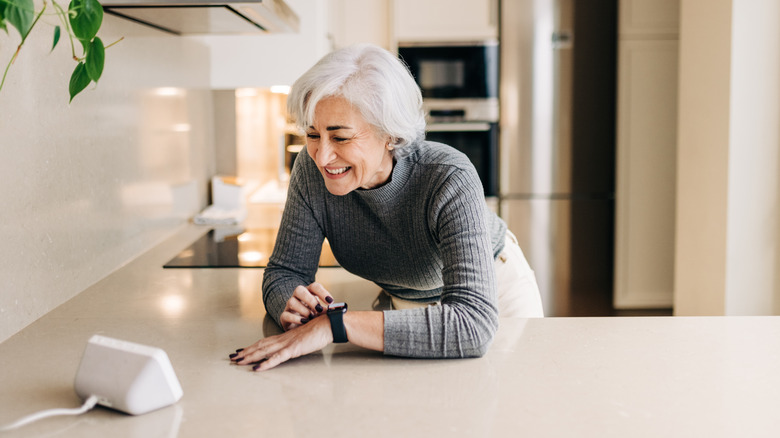 Old woman looking at gadget on kitchen counter