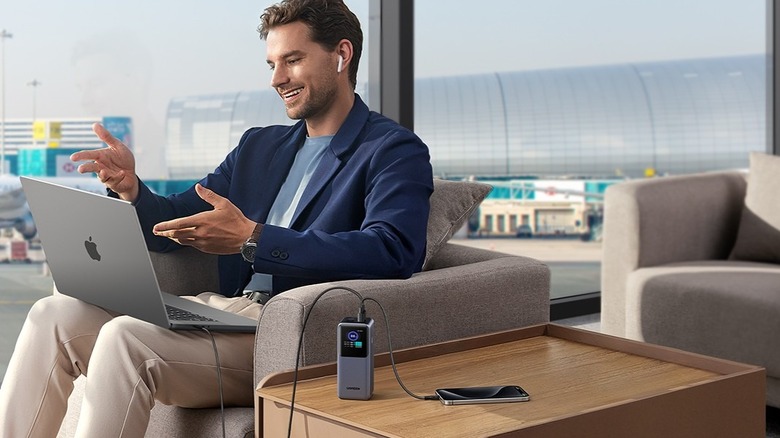 UGREEN Nexode Power Bank is pictured, sitting on desk next to a man wearing a blazer.
