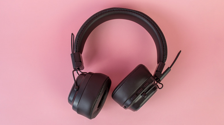 Black wireless headphones on a pink background