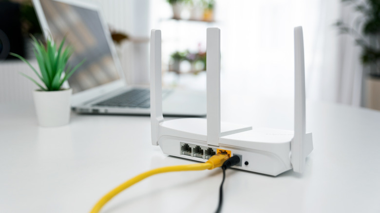 Modern Wi-Fi router on a counter next to a laptop in a home.
