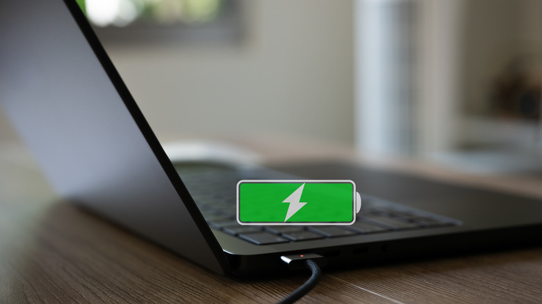 A laptop connected to a charger with a fully-charged battery symbol in the air